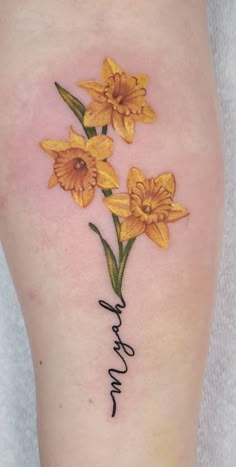 yellow daffodils tattoo on the right thigh and lower leg with words written in cursive writing