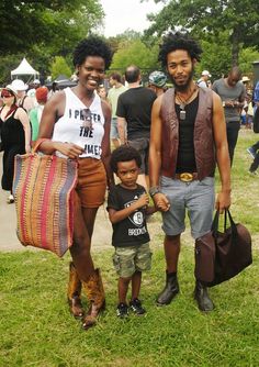 a man, woman and child standing in the grass at an outdoor event with other people