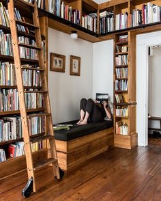 a person laying on top of a bed in front of a book shelf filled with books