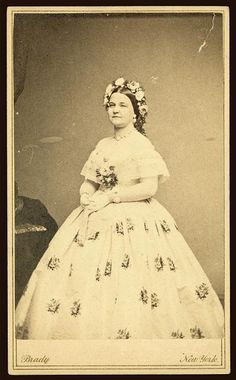 an old photo of a woman in a wedding dress with flowers on her head and shoulders