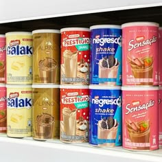 several cans of food are on display in a store shelf with the lids down and one is filled with milkshake