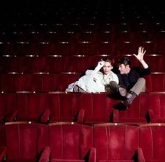 two people sitting in the middle of an empty theater