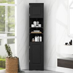 a tall black cabinet sitting next to a window in a white room with a basket on the floor