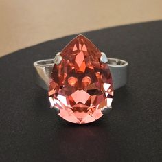 ♡ Genuine Austrian Crystal ♡ Solitaire Statement Ring ♡ 18x13mm pear shaped rhinestone (approx 3/4" x 1/2") ♡ Color: Rose Peach ♡ Shiny Silver plated (nickel free) ♡ Adjustable (measures size 9 1/2, adjustable 2 or more sizes up or down) ♡ Handcrafted with love and attention to detail Dazzling Pink Round Crystal Ring, Red Pear-shaped Cubic Zirconia Jewelry, Pink Pear-shaped Cubic Zirconia Ring, Orange Pear-shaped Jewelry, Rose Peach, Crystal Ring, Austrian Crystal, Shiny Silver, Crystal Rings