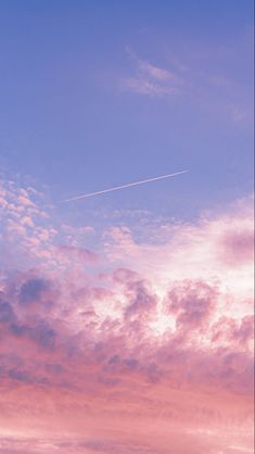 an airplane is flying high in the sky with pink clouds and blue skies behind it