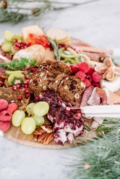 a platter filled with meats, cheeses and fruit on top of a table