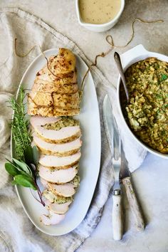 a white plate topped with sliced turkey next to a bowl of stuffing