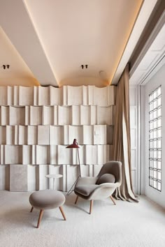 a chair and ottoman in front of a wall made out of concrete blocks, with a lamp on the side