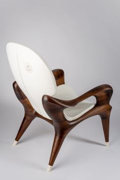 a white chair with wooden legs and an oval seat on the back, in front of a gray background