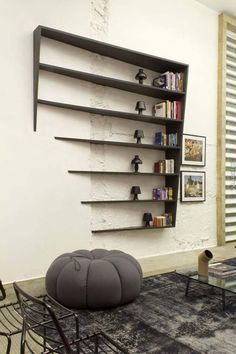 a living room filled with furniture and bookshelves next to a wall mounted book shelf