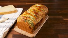 a loaf of bread sitting on top of a wooden cutting board next to a slice of cheese