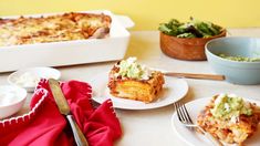 some food is sitting on plates near bowls and forks