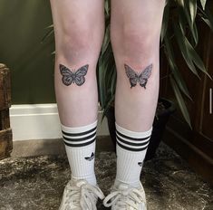 a woman's legs with two butterflies tattooed on their ankles and one is wearing white tennis shoes