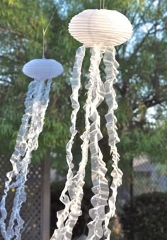 two white paper lanterns hanging from strings in the shape of jellyfishs and other sea creatures