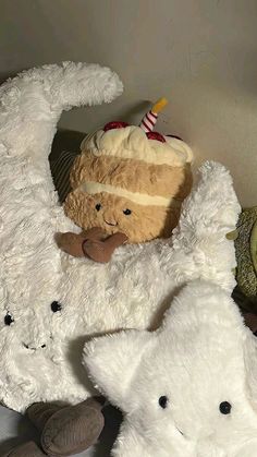 two white teddy bears sitting next to each other on a bed with a cake in the middle