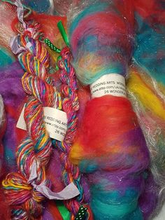 several skeins of multicolored yarn sitting in a pile together with labels on them