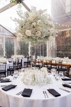 the centerpieces on this table are all white and have flowers in them, along with black napkins