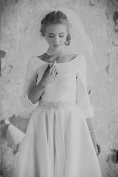 black and white photograph of a woman in a wedding dress holding her hand on her shoulder