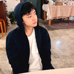 a young man sitting at a table with food in front of him and looking off into the distance