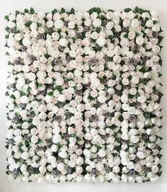 an arrangement of white flowers arranged on a wall