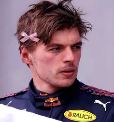 a close up of a person wearing a racing uniform with a bow in his hair