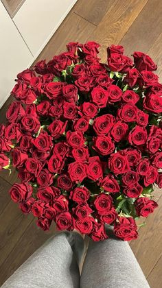 a bouquet of red roses sitting on top of a person's legs in front of a mirror