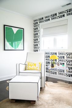 a white chair sitting in front of a window next to a painting on the wall