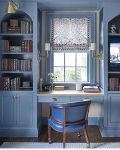 a blue chair in front of a window with bookshelves