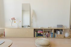 a living room with bookshelf, mirror and vases on the floor in front of it