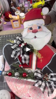 a santa clause sitting on top of a pink bowl filled with candy and other decorations