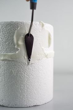 a toothbrush sticking out of a roll of toilet paper with white icing on it