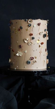 a white cake with flowers on it sitting on top of a black table next to a cloth