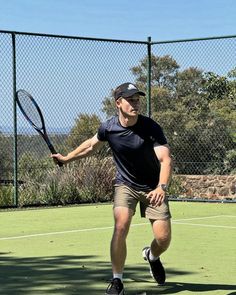 a man holding a tennis racquet on top of a tennis court in front of a fence