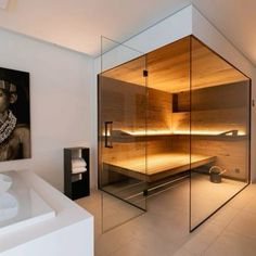 a glass walled sauna in the middle of a bathroom with a painting on the wall