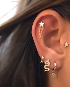 a woman wearing three different ear piercings on her left ear and one with two stars