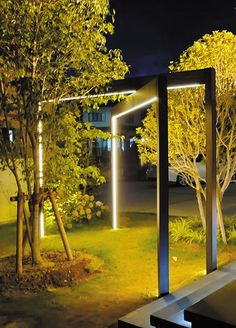 an outdoor area lit up at night with trees and benches in the foreground,