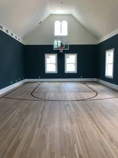 an empty basketball court in the middle of a room with blue walls and hardwood floors