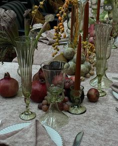 there are many glass vases on the table with fruit and vegetables around them,