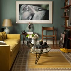 a living room filled with furniture and a painting hanging on the wall above a coffee table