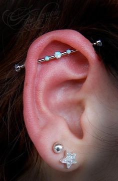 a woman's ear with three piercings on it