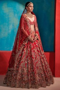 a woman in a red lehenga with gold jewelry on her neck and shoulders