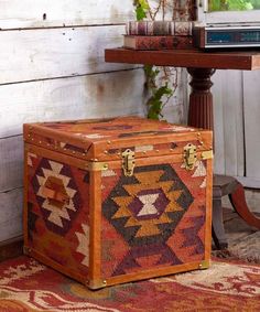 an old trunk sitting on top of a rug in front of a table with books