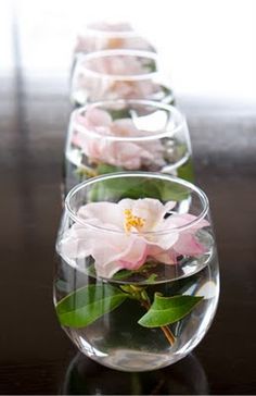 two vases filled with flowers on top of a wooden table next to each other