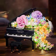 a piano with flowers on it sitting on top of a wooden table next to a toy piano