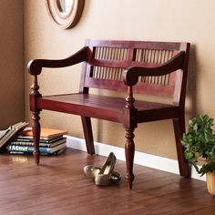 a wooden bench sitting on top of a hard wood floor next to a potted plant