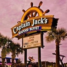 the captain jack's seafood buffet sign in front of palm trees and amusement rides