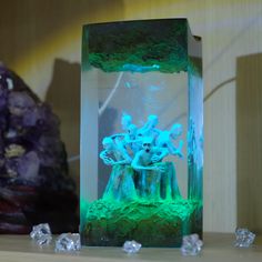 a green and blue sculpture sitting on top of a wooden table next to some rocks