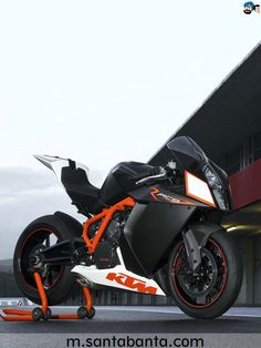 an orange and black motorcycle parked in front of a building