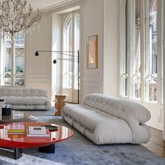 a living room filled with lots of furniture and a chandelier hanging from the ceiling