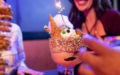 two women sitting at a table with ice cream and sprinkles in their glasses